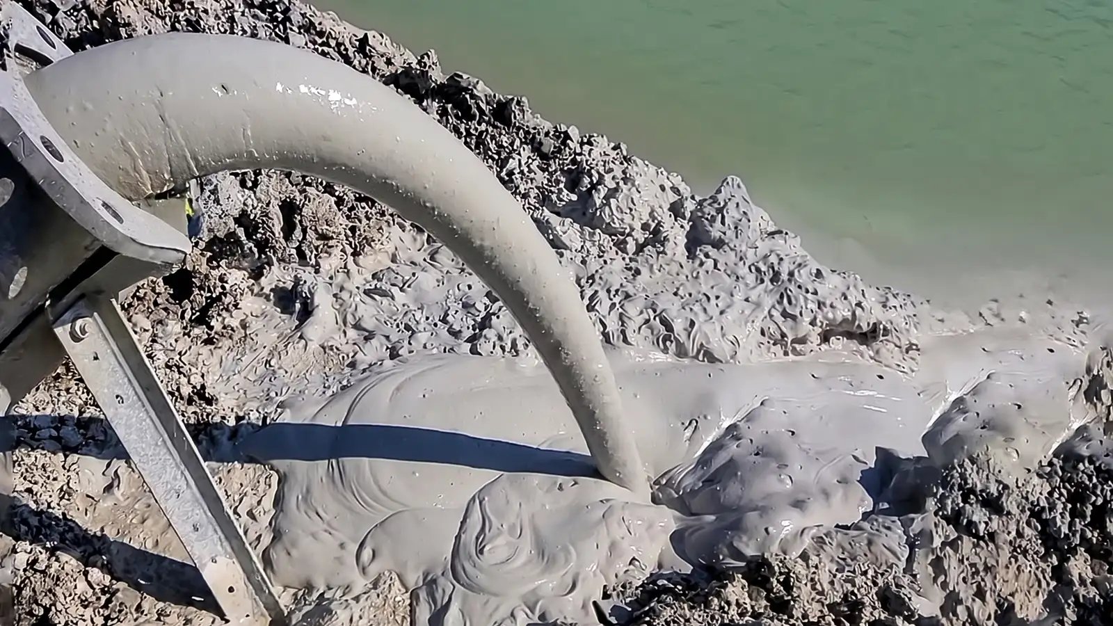Slurry discharge flowing through a pipeline during an industrial pumping operation, demonstrating real-world material transfer conditions that affect pump performance.