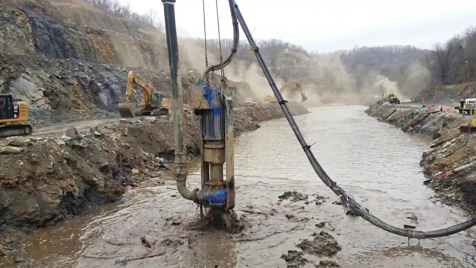 Modern hydraulic dredging system removing heavy sediment from a mining canal using an excavator-mounted pump for reliable, low-disruption canal maintenance and slurry transfer.