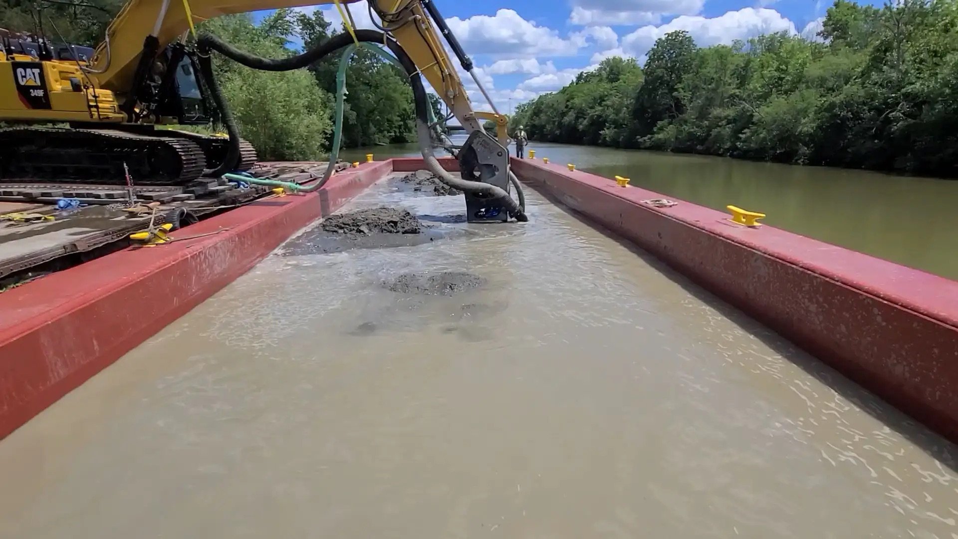Excavator attachment removing slurry from a water-filled channel during a dredging operation