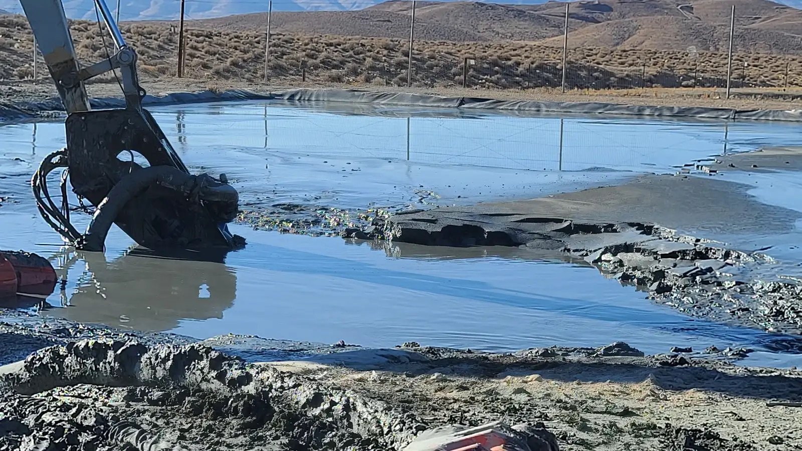 Excavator attachment working in a slurry pond with heavy sediment and solids handling conditions
