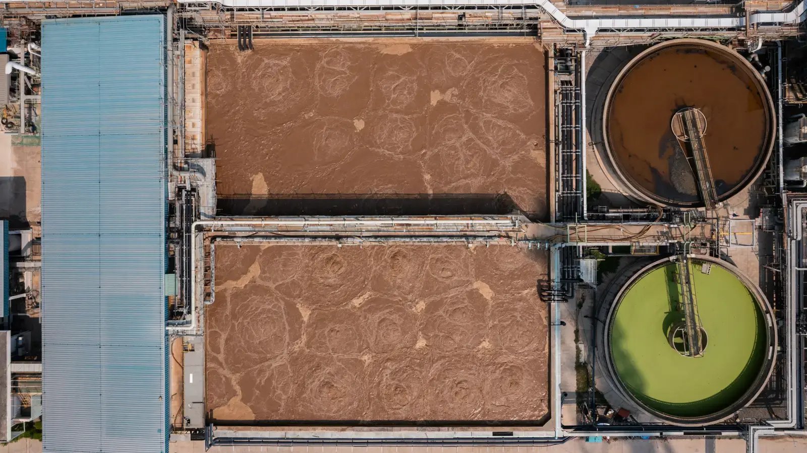 Aerial view of industrial wastewater basins and clarifiers, showing how site conditions shape hydraulic dredge equipment selection