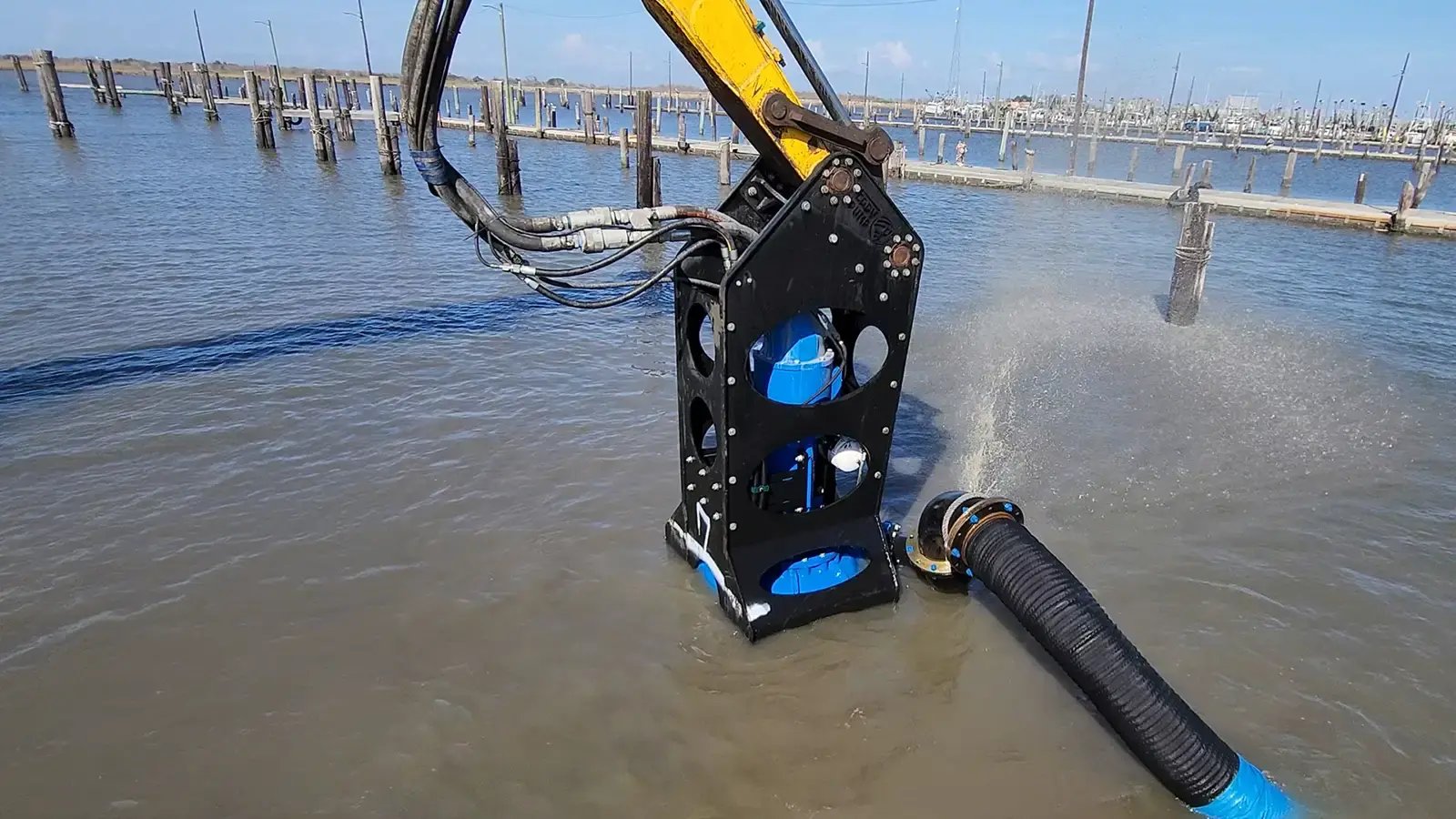 A boom-mounted dredge attachment submerged in turbid water