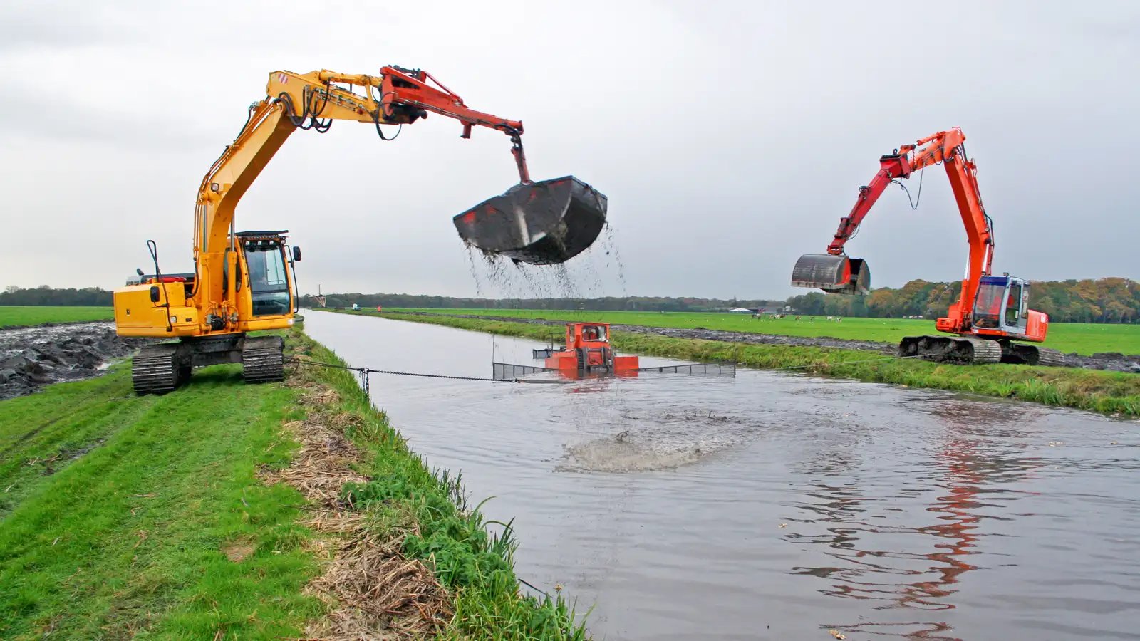 Excavators working along a canal to remove sediment and maintain water flow during dredging operations in minning industrry