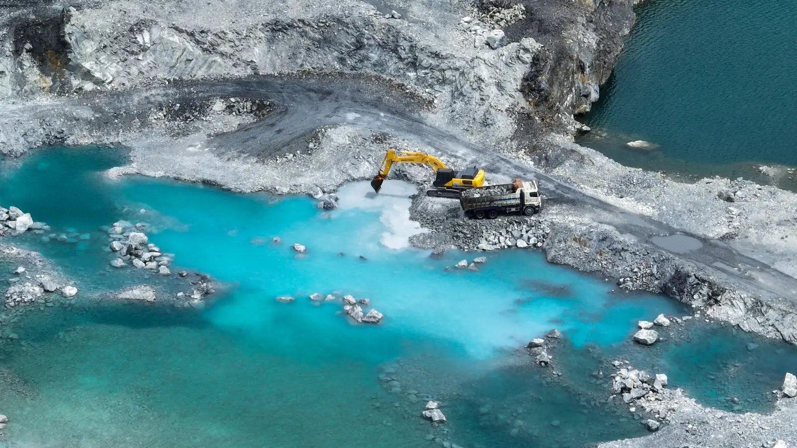 Quarry excavation beside a water channel illustrating how conventional dredging methods can increase downtime and operating costs compared to reliable modern dredging systems.