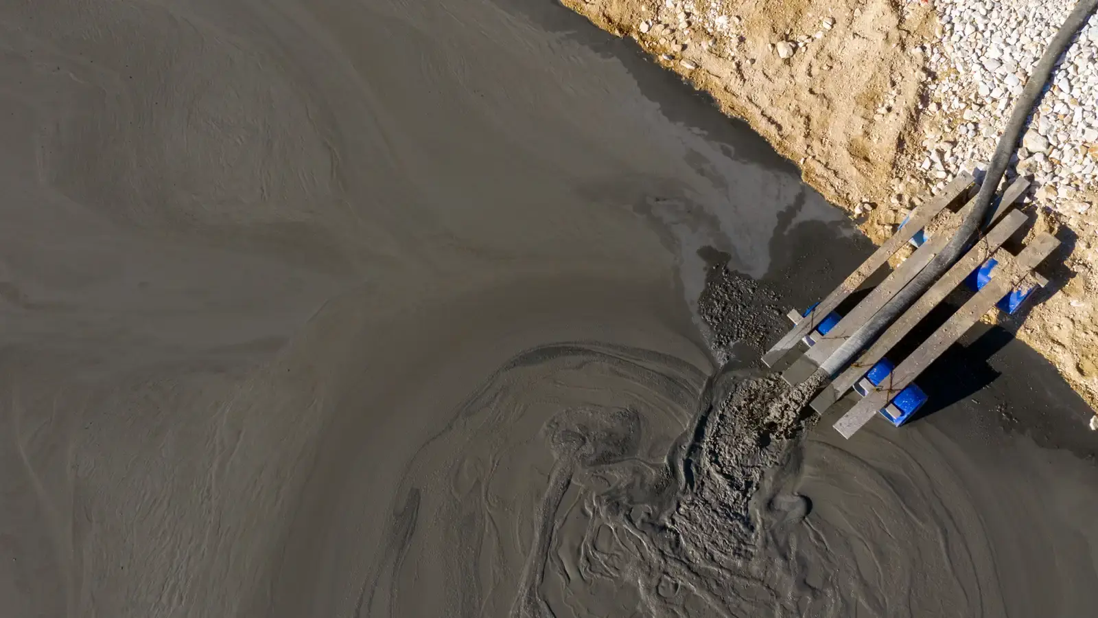 EDDY Pump slurry pump removing sediment buildup from mine process pond with brown water and settled debris visible